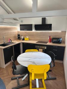 a kitchen with a white table and yellow chairs at LeLafayette in Metz
