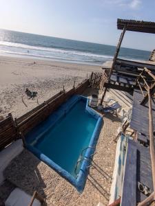 a swimming pool on a beach next to the ocean at Máncora Hostel Restocafebar in Máncora