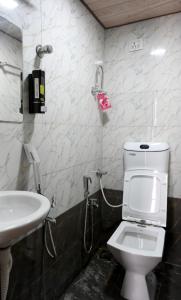 Un baño con un inodoro blanco y un lavabo. en Hotel Bhagirath, en Bombay