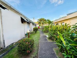 a walkway next to a white building with plants at Anoli Studio Location in Les Trois-Îlets
