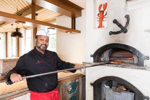 un hombre parado frente a un horno de pizza en Hotel Höfli, en Altdorf