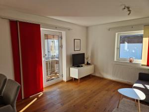 a living room with a couch and a tv and two windows at Ferienwohnung Lackner in Niedernsill