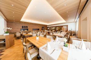 un restaurante con mesas de madera y mesas y sillas blancas en Hotel Höfli en Altdorf