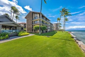 an exterior view of a house with a lawn and palm trees at Papakea L101 · PK L101 Maui Ground-Floor Condo with Ocean Views in Honokowai