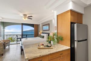 Un dormitorio con una cama y una cocina con nevera. en Lahaina Shores 607 · LS 607 Beachfront Remodeled Studio Stunnin, en Lahaina