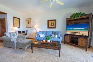 a living room with a blue couch and a tv at 412 Ridge in Kahana