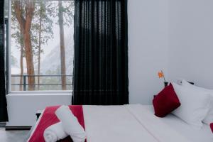 a bedroom with a bed with red and white pillows and a window at Auraya Ella in Ella