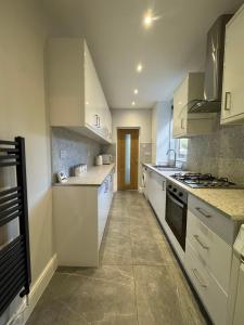 a large kitchen with white cabinets and appliances at Serenity LTD in Leicester