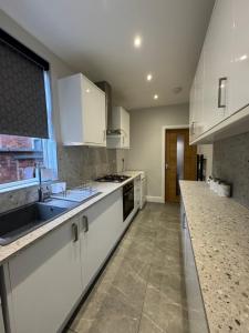 a kitchen with white cabinets and a sink at Serenity LTD in Leicester