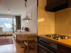 a kitchen with a stove and a living room at Retro Alpine Studio - Terrace with Mountain View in Leukerbad