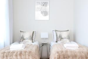 two twin beds in a room with white walls at Arctic Willamo Studio- Rovaniemi in Rovaniemi
