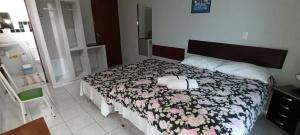 een slaapkamer met een bed met een bloemrijk dekbed bij Dormitório Dourada Costa in Baía Formosa