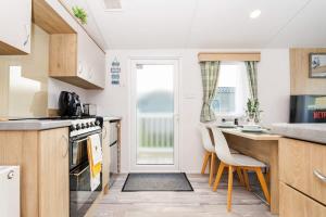 a kitchen with a counter and a table and chairs at 3Bed Caravan - Muirfield in Port Seton