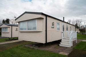 a small white house with a staircase in a yard at Seton Sands-3 Bed Static Caravan in Port Seton