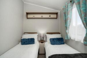 two beds in a small room with a window at Seton Sands-3 Bed Static Caravan in Port Seton
