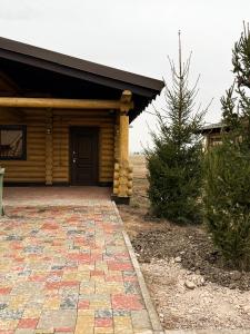 a house with a brick walkway in front of a building at Дом из сруба in Koshi