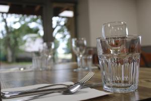 Sainte-EulalieにあるEspace Gerbierのグラスとフォークとナイフが置かれた木製のテーブル