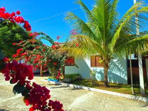 a house with palm trees and flowers in front of it at Temporada Belas Casas in São Pedro