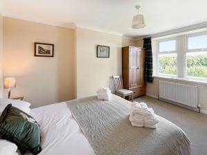 une chambre avec un grand lit blanc avec des serviettes dessus dans l'établissement Kilquhanity Cottage, à Castle Douglas 10 autres photos