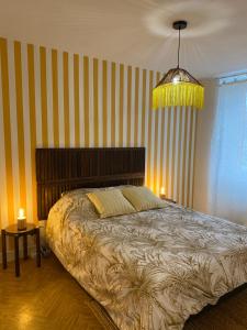 ein Schlafzimmer mit einem großen Bett und einer gelb gestreiften Wand in der Unterkunft Gîte Minimalist indépendant au calme in Commentry