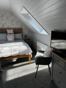 a bedroom with a bed and a chair in a attic at Dunroamin Bed and Breakfast in Aviemore