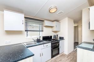 a kitchen with white cabinets and black counter tops at 3Bedroom Caravan Seton Sands in Port Seton