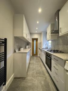 レスターにあるSerenity LTDの白いキャビネットと家電製品を備えた広いキッチン