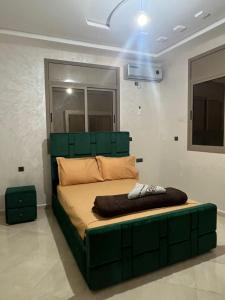 a bed with a green headboard in a room at Sahara luxury suites in Hassilabied