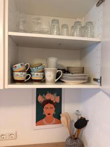 uma prateleira com pratos, xícaras e a foto de uma mulher em Renovated apartment near Büdingen with single beds em Büdingen