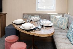 a wooden table with plates and glasses on a couch at 3 Bed Caravan - Seton Sands in Port Seton +20 photos