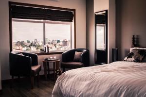 a bedroom with two chairs and a bed and a window at Point Boutique Hotel in Phnom Penh