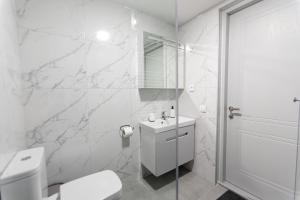 a white bathroom with a toilet and a sink at GGM apartment in Kutaisi +22 photos