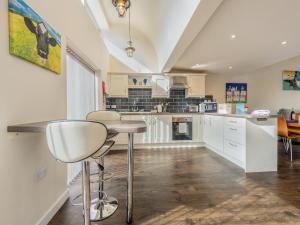 a kitchen with white cabinets and a bar stool at The Parlour in Ferndown