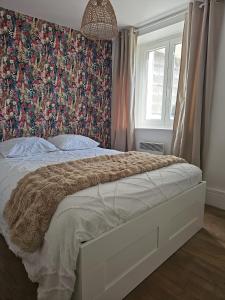 a bedroom with a large bed with a floral wallpaper at Appartement coquet à la Machine in La Machine