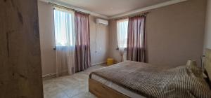 a bedroom with a bed and two large windows at Zeytoun Guest House in Yerevan