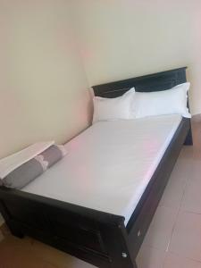 a bed with white sheets and pillows in a room at Guardian Motel Kasese in Kasese