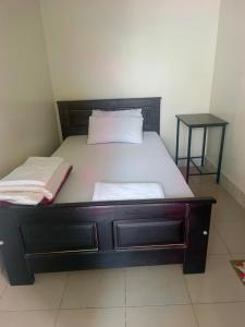 a bed with a wooden headboard and a night stand at Guardian Motel Kasese in Kasese