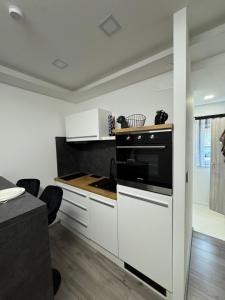 a kitchen with white cabinets and a black oven at Lux Stay Apartmant in Varaždin