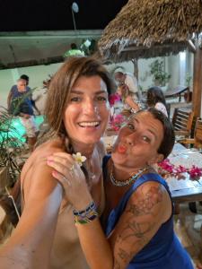 two women sitting next to each other at a table at Peace And Color Limited Guest House in Nungwi +160 photos