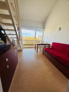 ein Wohnzimmer mit einem roten Sofa und einem Balkon in der Unterkunft T2 4 couchages Port du Cap d'Agde , climatisation , piscine in Cap d'Agde