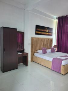 a bedroom with a bed and a table and purple curtains at Cielstar Resort in Anuradhapura +64 photos