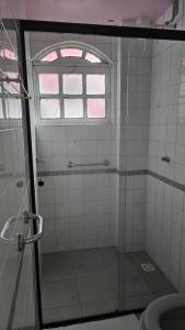 a bathroom with a glass shower with a window at Flor de Laranjeira Guest House in São Pedro da Aldeia