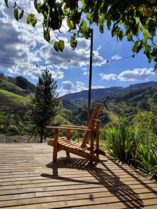 Un banco de madera situado encima de una plataforma de madera. en Alto Maanaim, en Sapucaí-Mirim