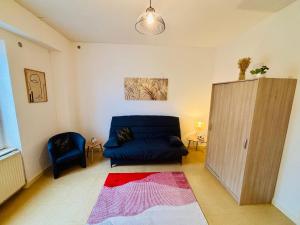una sala de estar con un sofá y una silla en Le pied à terre - Centre ville - Montceau-les-mines, en Montceau-les-Mines
