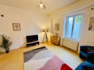 Una sala de estar con televisión y un sofá. en Le pied à terre - Centre ville - Montceau-les-mines, en Montceau-les-Mines