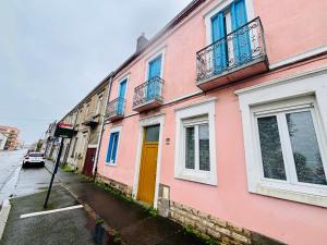 un edificio rosa con una puerta amarilla en una calle en Le pied à terre - Centre ville - Montceau-les-mines, en Montceau-les-Mines