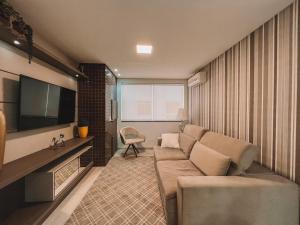 ein Wohnzimmer mit Sofa und Fernseher in der Unterkunft 2 Dorm a 100 metros do mar in Capão da Canoa