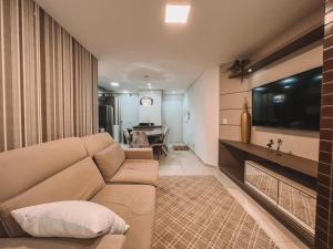 ein Wohnzimmer mit einem Sofa und einem Fernseher an der Wand in der Unterkunft 2 Dorm a 100 metros do mar in Capão da Canoa + 5 Fotos