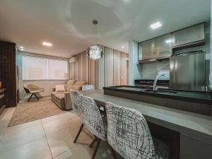 eine Küche und ein Wohnzimmer mit einer Theke und Stühlen in der Unterkunft 2 Dorm a 100 metros do mar in Capão da Canoa