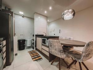 eine Küche mit Tisch und Stühlen und einem Kühlschrank in der Unterkunft 2 Dorm a 100 metros do mar in Capão da Canoa